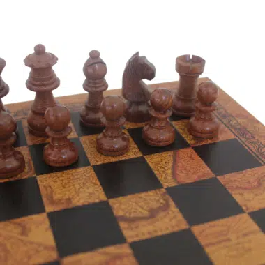 Gros plan sur les pièces d'échecs sombres en bois d'acacia sur plateau motif carte du monde vintage